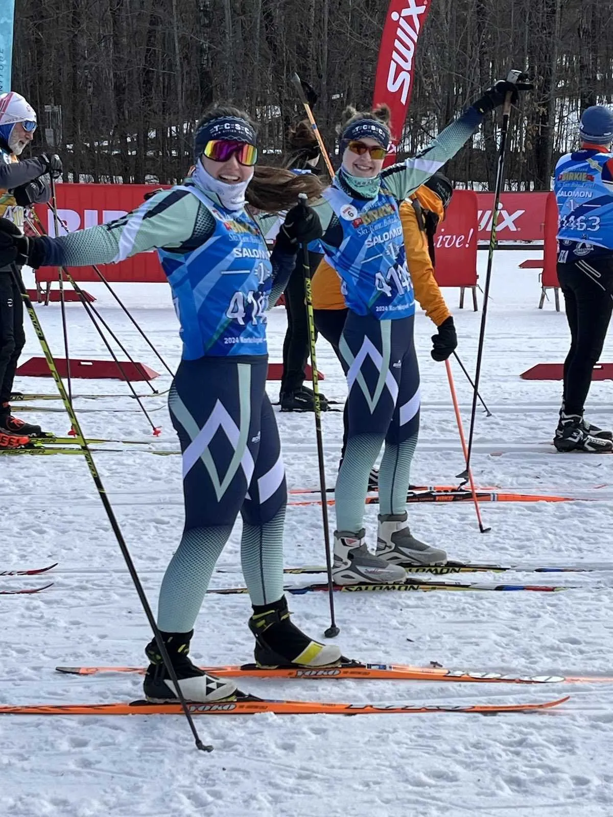 Two members in matching TCSC kits with arms raised at the Birkie start area